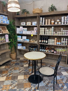 Cozy cafe shop interior with shelves of goods, a round table, and a chair on patterned tile floor