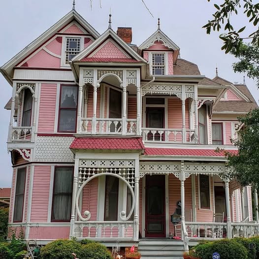Pink Victorian house with white gingerbread trim, balconies, and a covered front porch