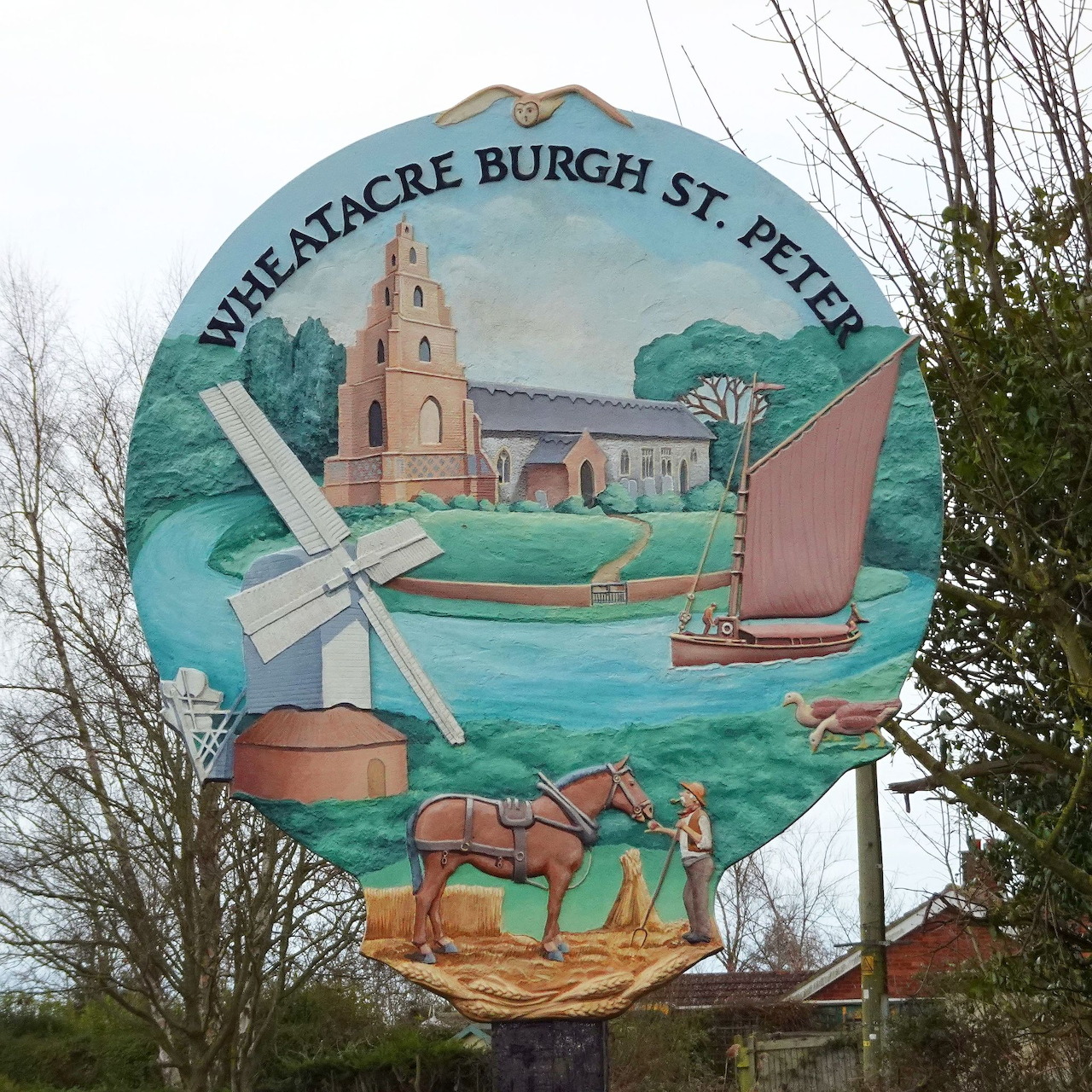 Wheatacre Burgh St. Peter village sign showing church, windmill, boat, horse cart, and wheat sheaf