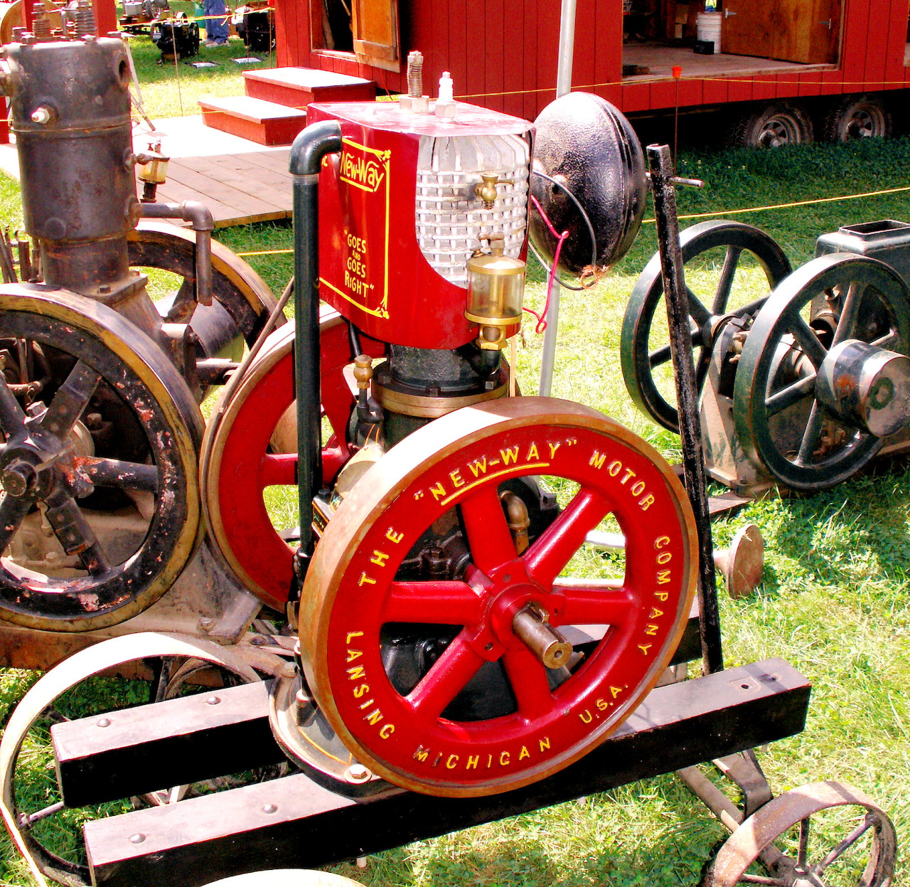 Restored red New-Way stationary engine on display outdoors with antique machinery
