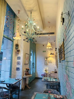 Cozy cafe interior with turquoise chandelier, pastel brick walls, and vintage decor