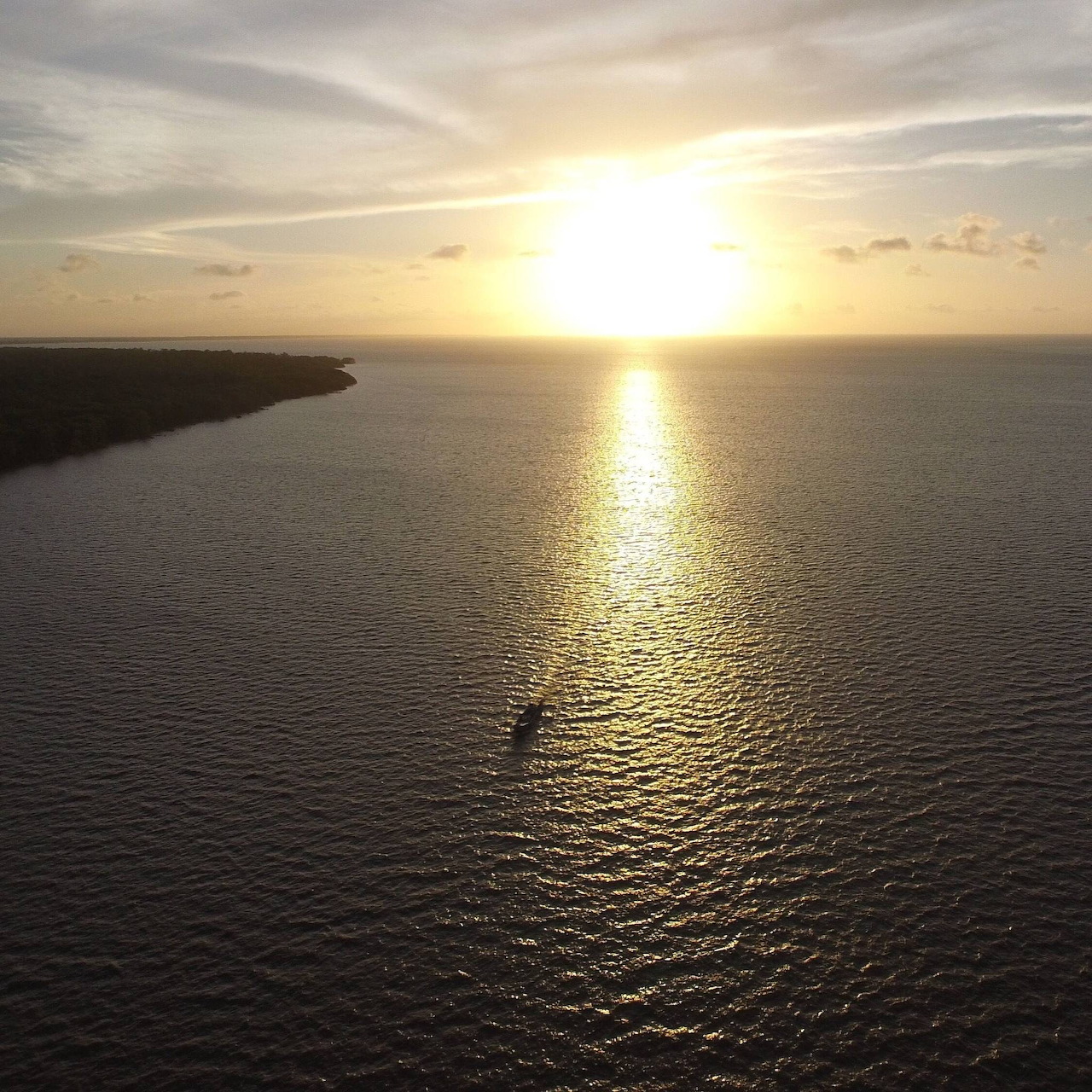 Aerial sunset view over calm ocean with boat near Suriname coastline