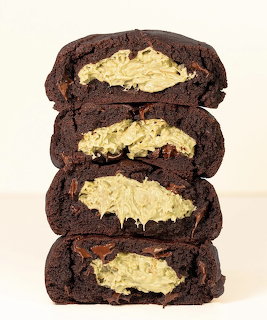 Stack of four halved dark chocolate cookies showing creamy filling inside on white background