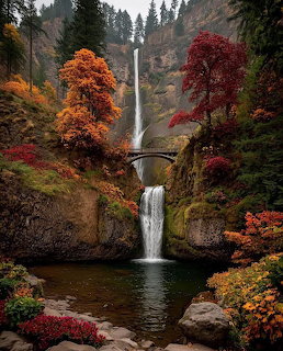 Multnomah Falls cascading down a cliff with colorful autumn trees and a stone bridge