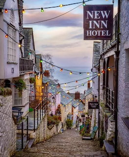 Steep cobbled street in Clovelly Devon at twilight with colorful houses and string lights