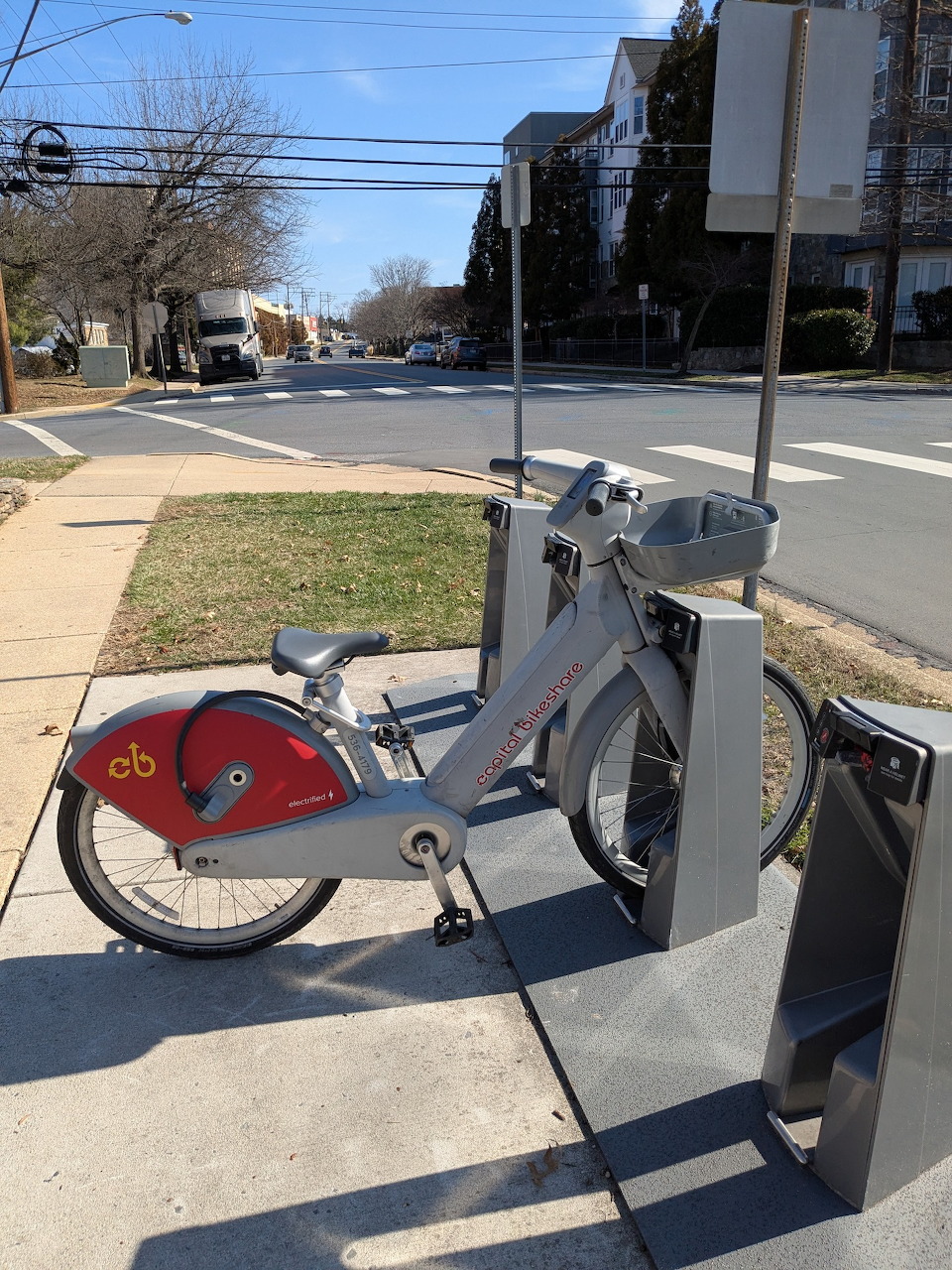 Row of parked rental bikes at an outdoor docking station with one slot empty.