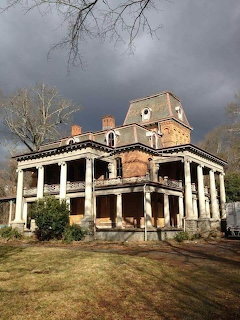 Abandoned Victorian mansion with columns under dark storm clouds