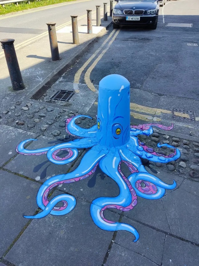 Blue octopus street art painted on gray pavement with spreading tentacles