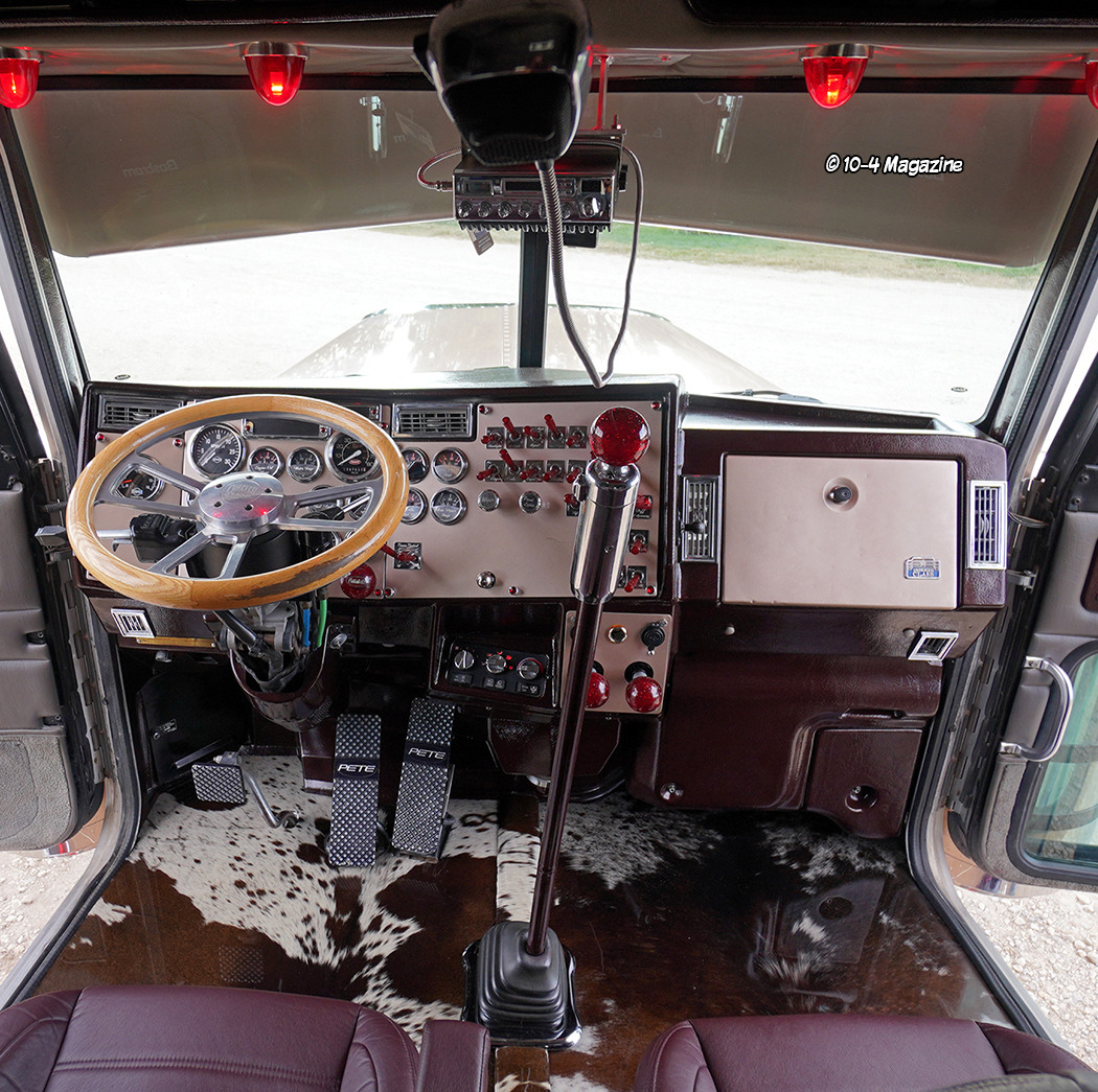 Interior cabin of Peterbilt 379 truck with dashboard, wood-grain steering wheel, and purple seats