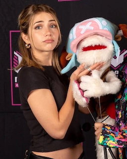 Woman in black crop top smiling while holding large plush shark toy