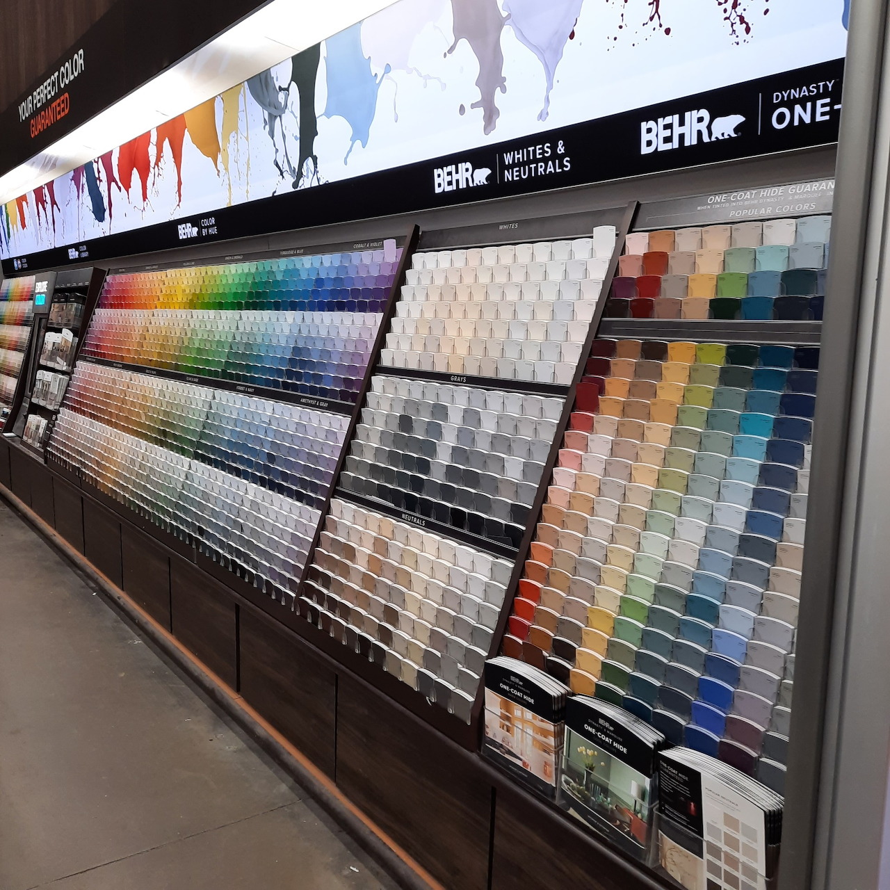 Retail paint department wall display with organized rows of color sample chips in rainbow gradients