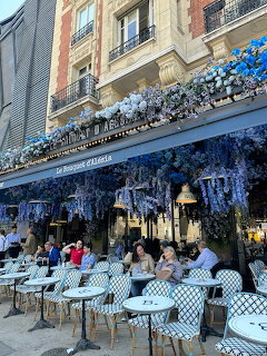Paris cafe terrace with blue floral decorations and outdoor tables filled with diners