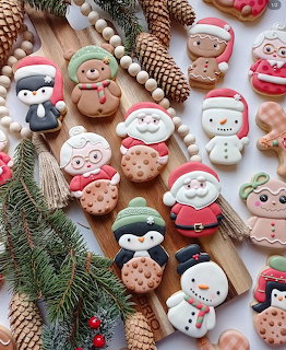 Decorated Christmas cookies with holiday characters arranged with evergreen branches and pinecones