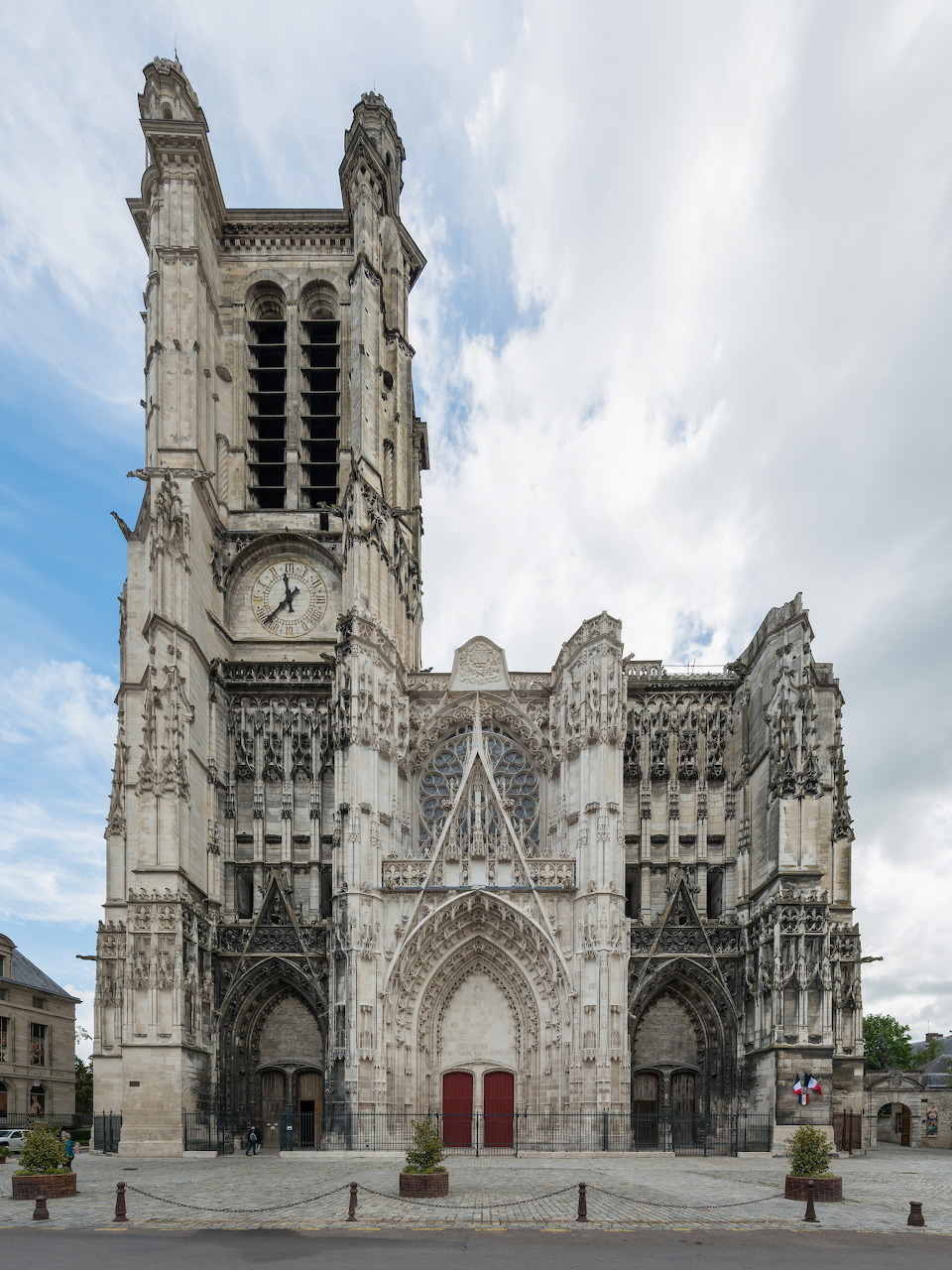 Gothic cathedral facade with twin towers and red doors in a town square