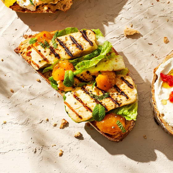 Open-faced toast with grilled halloumi, lettuce, mint, and orange segments
