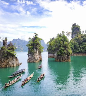Limestone karst pillars in turquoise lake with longtail boats and tropical greenery in Thailand