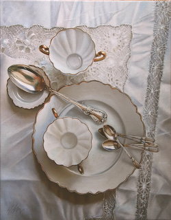 White porcelain dishes and silver spoons arranged on a lace tablecloth