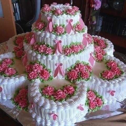 Multi-tier white cake with pink rose decorations and heart-shaped cake pieces on a table
