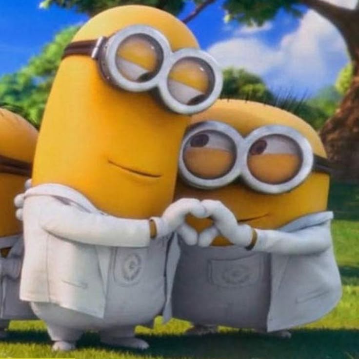 Two Minions in white outfits making a heart shape with their hands outdoors