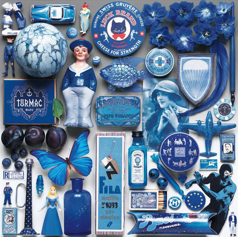 Flat lay arrangement of assorted blue objects and trinkets on white surface