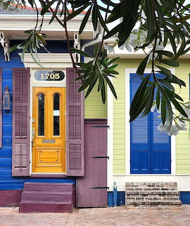 Row of colorful houses with yellow door, blue shutters, pink and yellow walls, and tropical plants