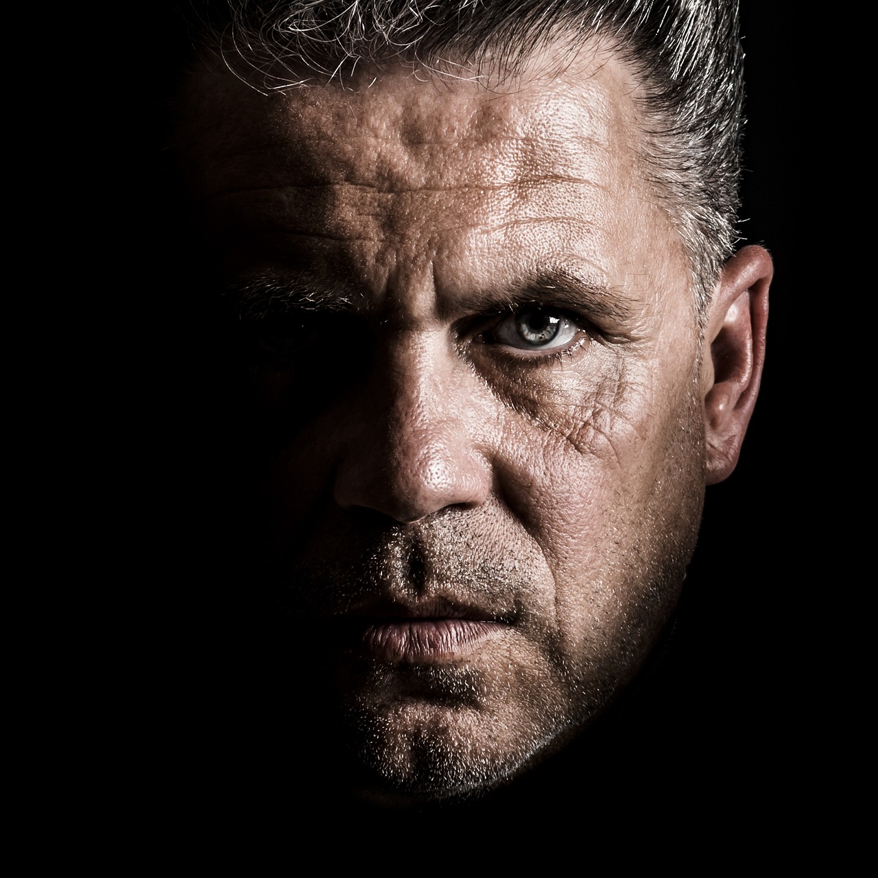 Close-up portrait of man with intense expression on dark background