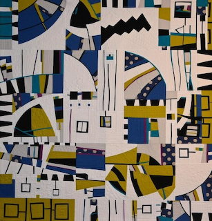 Abstract quilt with geometric shapes in blue, yellow, black, and white creating a bold modern pattern