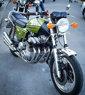 Green vintage Benelli 750 Sei motorcycle with chrome engine and headlight on gray pavement