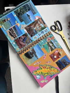 Open scrapbook with vacation photos of beaches, wildlife, and landscapes next to gold scissors