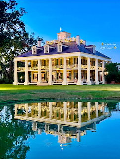 Historic columned plantation mansion with Christmas lights reflected in a pond at twilight