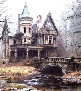 Abandoned Victorian stone castle with turret and arched stone bridge over a stream in a bare winter forest