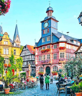 Colorful half-timbered buildings and clock tower in Heppenheim town square with outdoor café seating