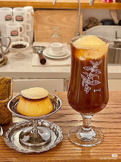 Cold brew coffee float and Japanese custard pudding on silver dessert stands at a cafe counter
