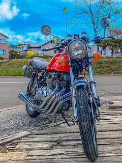 Red Honda 400 Four vintage motorcycle parked on street with chrome details and round headlight
