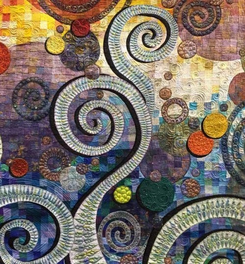 Colorful abstract quilt with spiral motifs, circles, and textured patchwork fabric