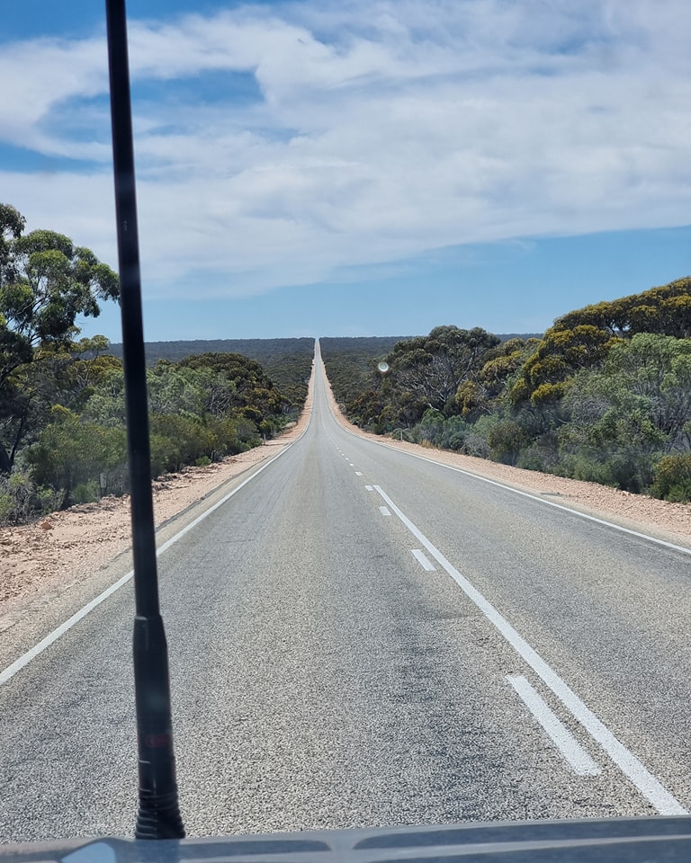 Long straight highway vanishing into the horizon through Australian outback scrubland
