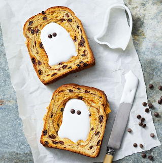 Two ghost-decorated toast slices with fruit and chocolate chips on parchment