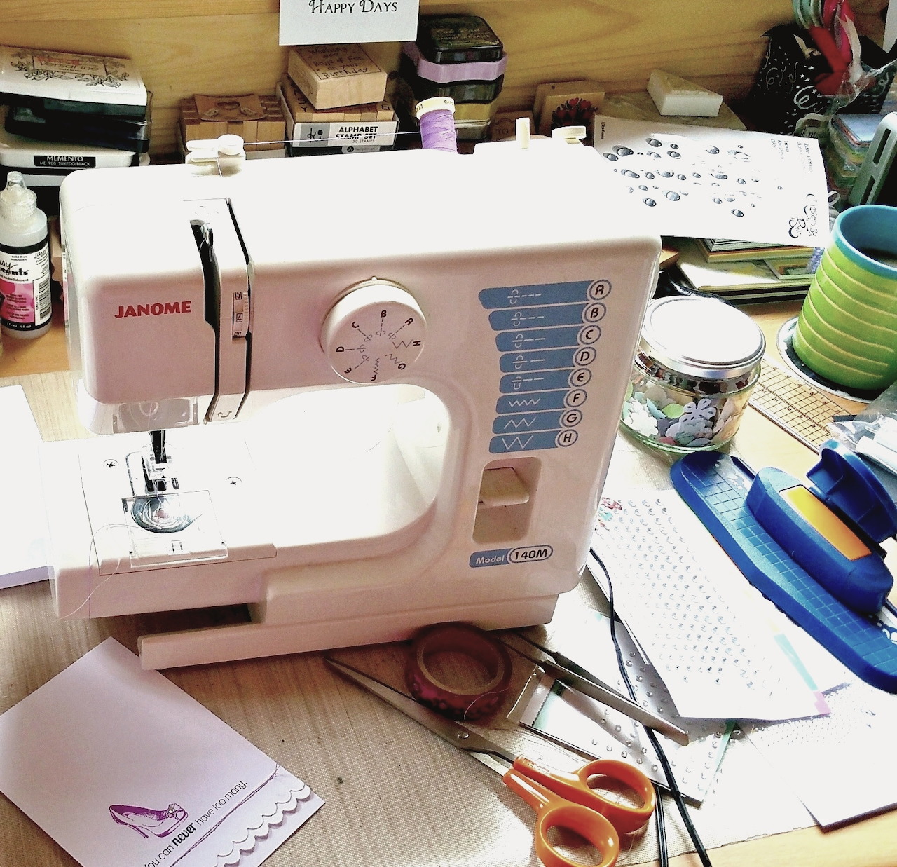 Pink sewing machine on craft table with scissors, paper, and supplies