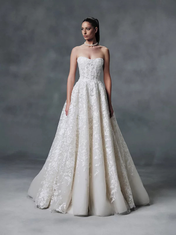 Woman in a strapless white lace wedding gown standing in a studio