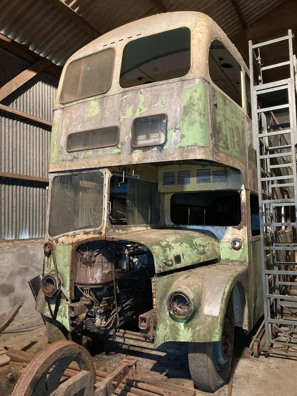 Weathered vintage Daimler double-decker bus shell inside a shed