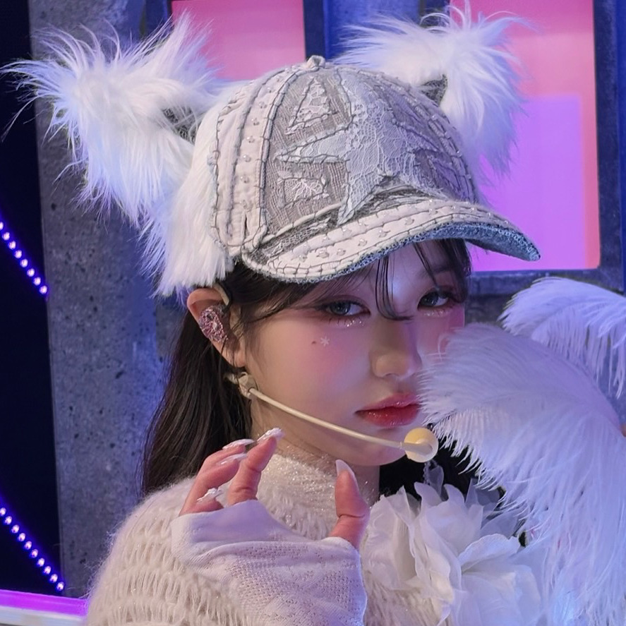 Young woman in sparkly cat ear cap with white fur trim holding a lollipop on stage