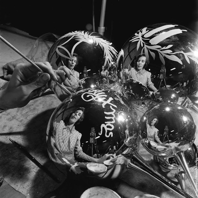 Black-and-white close-up of a hand painting shiny Christmas ornaments