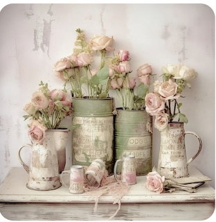 Soft pink roses in vintage metal pitchers and tins on a rustic table