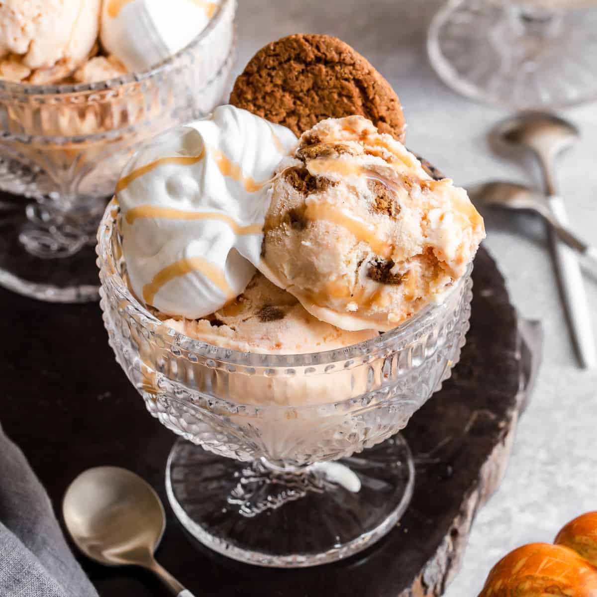 Pumpkin ice cream in a glass bowl topped with whipped cream and cookie crumbles