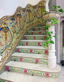 Ornate Art Nouveau staircase with floral ceramic tiles and curved iron railing with ivy