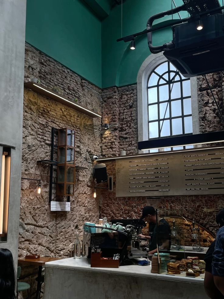 Rustic cafe interior with exposed brick, arched window, teal ceiling, and vintage wooden furniture