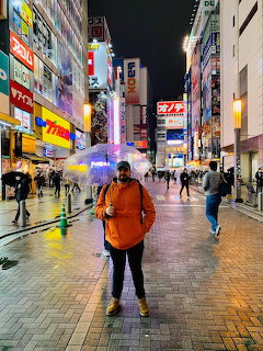Person with clear umbrella standing on a rainy neon-lit Tokyo street at night