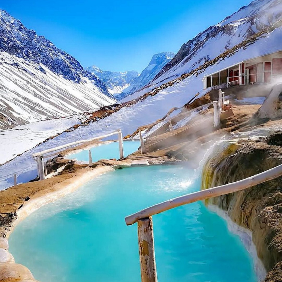 Turquoise hot spring pools surrounded by snow-covered mountains
