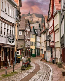 Cobblestone street in Marburg old town with half-timbered houses and a castle on the hill