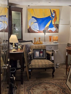 Antique shop interior with vintage chair, cabinet, lamps, mirrors and colorful abstract painting